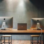 Minimalist office space with dual monitors on a wooden table, promoting a contemporary work environment.